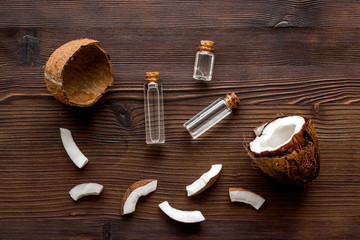 Coconut cosmetics. Organic oil in small bottles on dark wooden background top-down