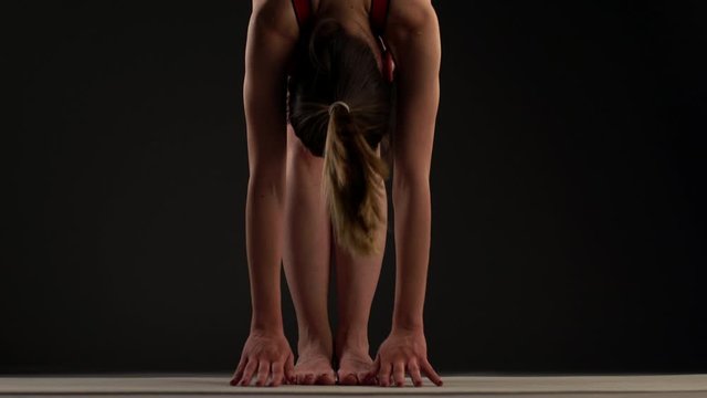 Girl practicing yoga. Stretching arms and legs. Hands touching feet and gorund.