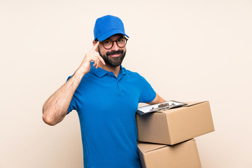 Delivery man with beard over isolated background with glasses and smiling