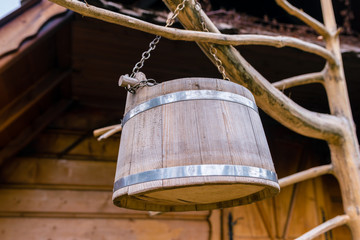 Simple wooden bucket for milking sheep and cows drying on the tree in front of the shepherd's hut