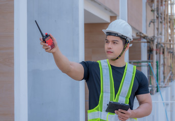 Handsome and strong foreman.Strong foreman wearing a white helmet, holding a radio communication...