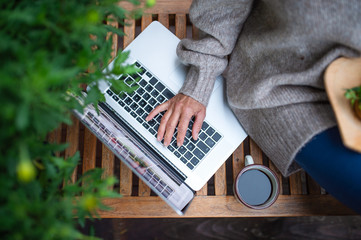 Top view of senior woman with laptop sitting outdoors on terrace, working.