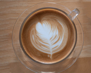 Top view of hot coffee latte cup with beautiful art shape on the table