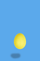 Flying golden egg with light blue background, easter minimal concept with empty space for text