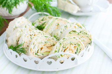 Spring pita roll with fresh cucumber, egg and cheese on a white dish with fresh herbs, horizontal