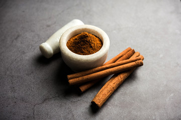 Obraz na płótnie Canvas Powder cinnamon and sticks also known as Dalchini or Dalcheenee masala from India, selective focus