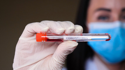 Nurse holding test tube with blood for Coronavirus (nCoV) analyzing. Novel Chinese, Close-up portrait of a girl in a mask of exhilaration with suspected coronavirus. 