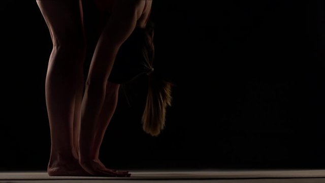 Girl practicing yoga. Stretching arms and legs. Hands touching feet and gorund.