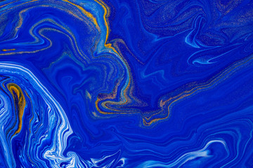 Fluid art texture. Abstract background with mixing paint effect. Liquid acrylic picture that flows and splashes. Classic blue color of the year 2020. Blue, golden and white overflowing colors