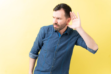 Latin Man Is Cupping Ears Over Colored Background
