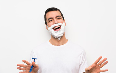 Man shaving his beard over isolated white background smiling
