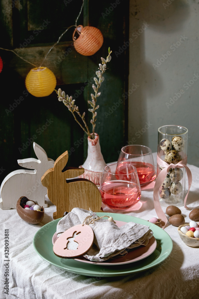 Wall mural easter table setting with wooden rabbit decoration, chocolate eggs and sweets, glasses of pink cockt