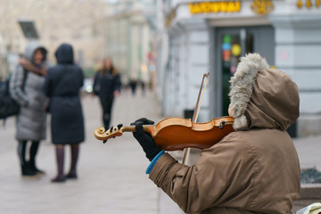 Photography of a street musician plays the violin on a city street on a spring day. Backs / rear...