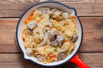 Step-by-step cooking sauerkraut stew with meat, step 4 - adding sauerkraut to meat and onions and stewing them together, top view, horizontal