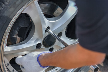 a After a breakdown, a person changes a wheel on a car to another wheel with a wrench