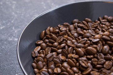 coffee beans in dark bowl cup on isolated dark textured background