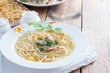Homemade chicken broth soup with homemade egg noodles, horizontal, copy space