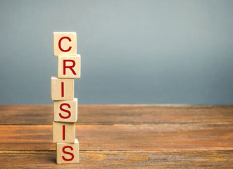 Falling wooden blocks with the word Crisis. Instability of business and economy. Recession, stagnation, bankruptcy. Midlife crisis. Impoverishment. Risks and debts