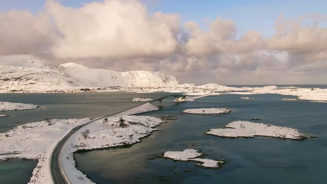 snow covered lofoten landscape aerial shot drone flying up over fredvang bridges at sunrise