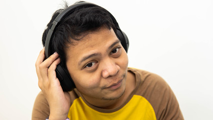Close-up portrait of happy Asian man smiling while enjoying listen to music on white isolated background.