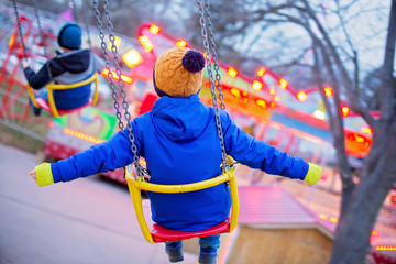 Obraz na płótnie Canvas Child, cute boy riding chain swing carousel on sunset, motion blur