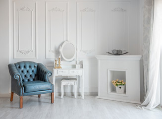 White room with blue retro chair and mirror.