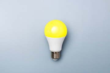 switched on led bulb with yellow light on grey background with copy space for advert. business idea concept