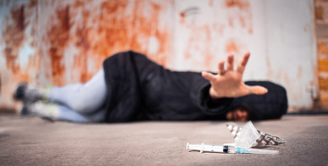 Woman lying on the floor reaches for drugs. Dependence, abuse, intoxication, despair, dose syringe and pills. Social issue among adolescents. The concept of anti drugs