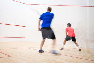 Squash players in action on a squash court (motion blurred image; color toned image)