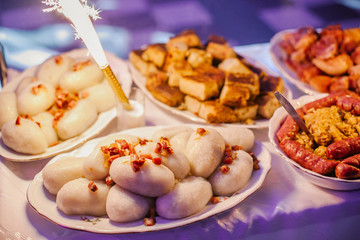 Potato dumpling with meat. Polish wedding catering table. Potato cake and sausage with cabbage. Typical Poland vintage rustic homemade food background. 