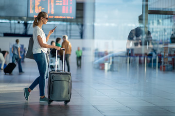 Young woman with her luggage at an international airport, before going through the check-in and the...