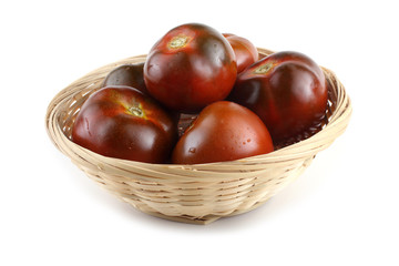Dark tomatoes on wicker plate
