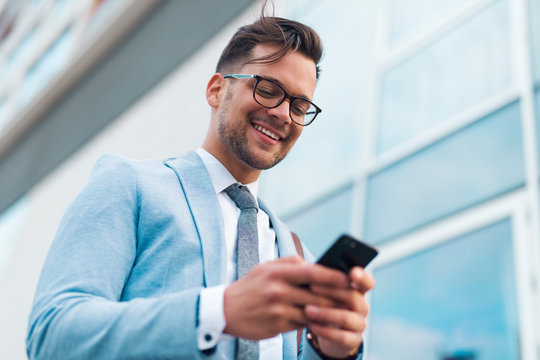Young businessman in suit using phone.