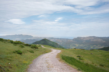Road between the mountains with walkers walking on a cloudy day in Asturias, Spain.