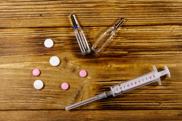 Concept of a prevention and treatment coronavirus. Pills, syringe, ampoules on a wooden background....