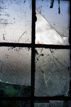 Cracked window panes in derelict farmhouse