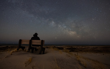 Naklejka na ściany i meble Stargazer - Man on a bench looking at the Milky Way 