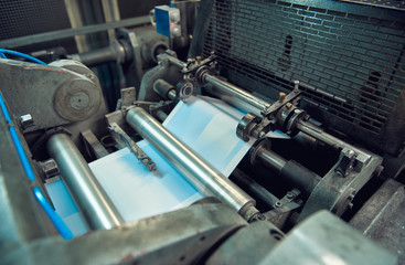 A industrial commercial envelope making machine, making paper envelopes for international distribution. Automated engineering machinery for mass production of paper envelopes.