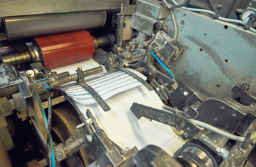 A industrial commercial envelope making machine, making paper envelopes for international distribution. Automated engineering machinery for mass production of paper envelopes.