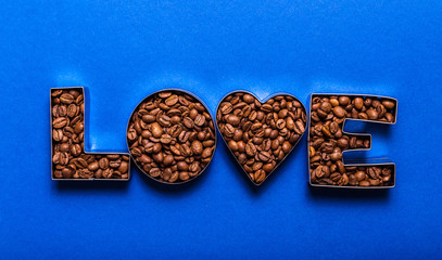Lettering love made from coffee beans on a blue background. Coffee love concept