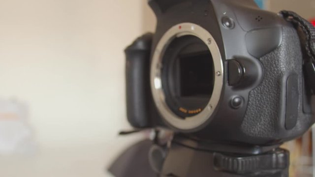 The lens is detached from the camera mount. A man's hand presses the lens mount button and detaches the lens from the camera. Close-up of disconnecting lens from the camera