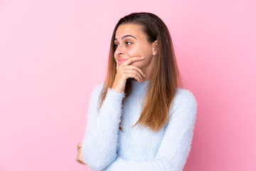 Teenager girl with blue sweater over isolated pink background thinking an idea