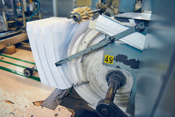 A industrial commercial envelope making machine, making paper envelopes for international distribution. Automated engineering machinery for mass production of paper envelopes.
