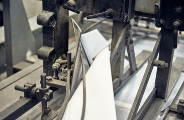 A industrial commercial envelope making machine, making paper envelopes for international distribution. Automated engineering machinery for mass production of paper envelopes.