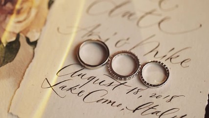 Wedding rings and the bridal engagement ring lie on the card with wedding day invitation, written in the beautiful font