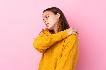 Teenager girl with yellow sweater over isolated pink background suffering from pain in shoulder for having made an effort
