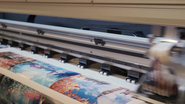 Industrial printing on woven material, modern digital inkjet printer puts a picture on a cloth canvas