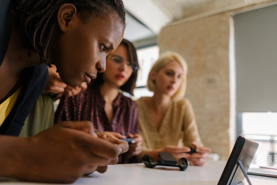 Focused afroamerican woman and her small tech startup team having fun testing new game for a console