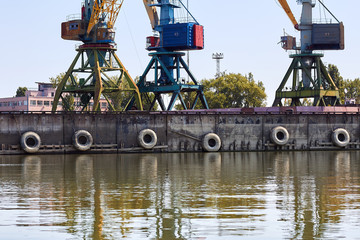 Cranes in cargo port translating coal. Industrial scene. Big port-cranes. Danube river
