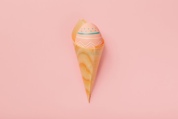 Colored decorated egg in bamboo cones looks like ice cream on pink background. Concept of Easter, zero waste, ecology